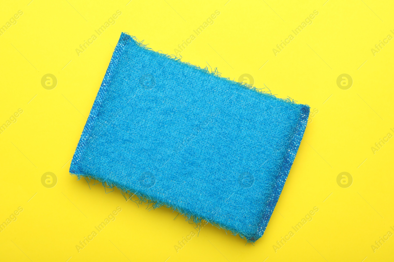 Photo of One blue sponge on yellow background, top view