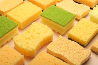 Photo of Many colorful sponges on beige background, closeup