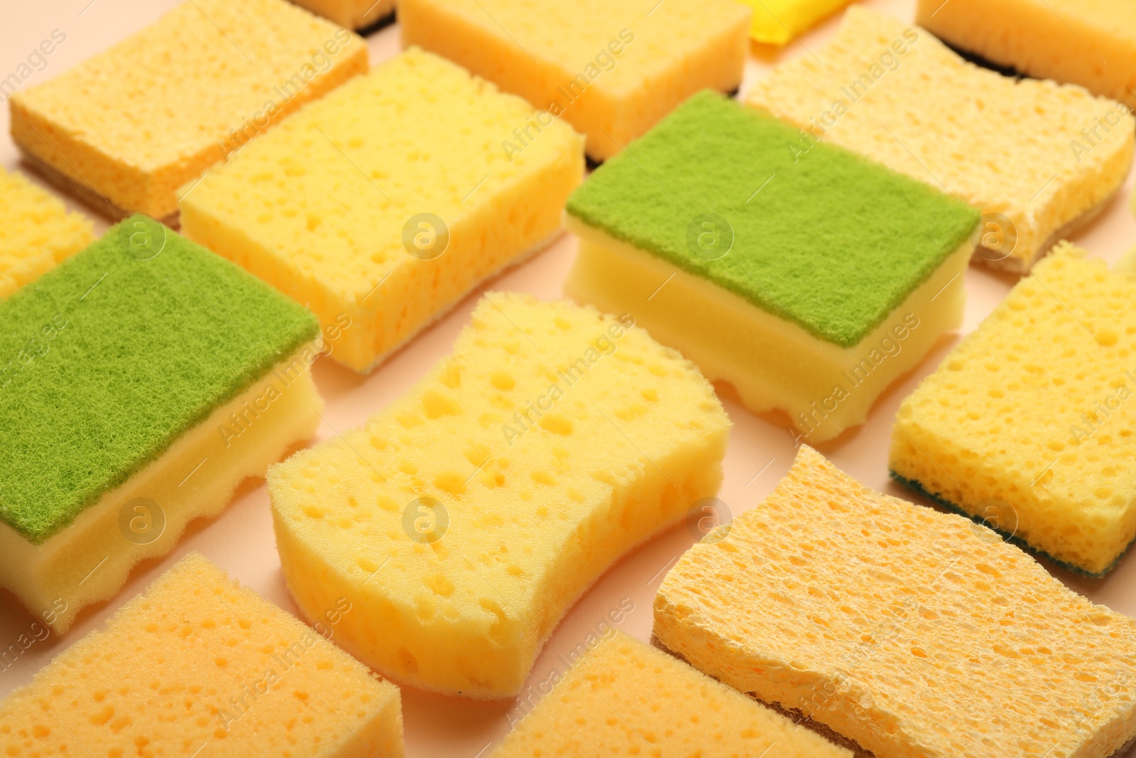 Photo of Many colorful sponges on beige background, closeup