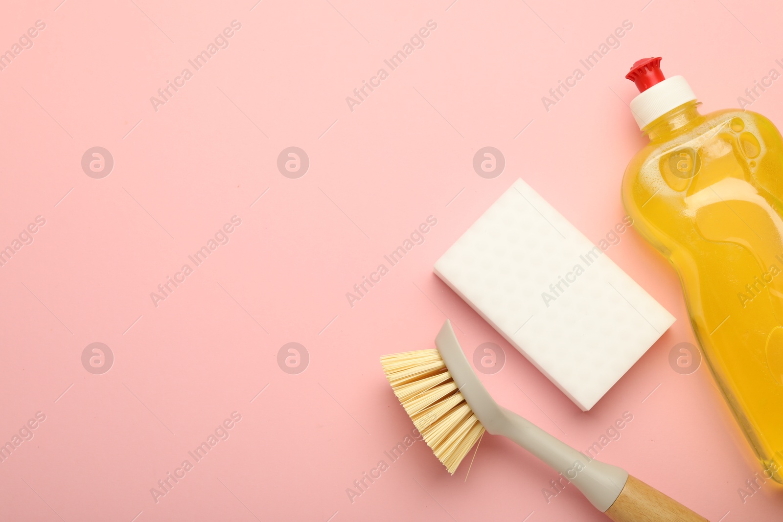 Photo of Sponge, brush and detergent on pink background, flat lay. Space for text