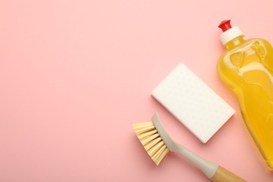 Photo of Sponge, brush and detergent on pink background, flat lay. Space for text