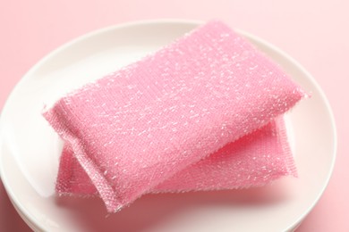 Sponges and stack of plates on pink background, closeup