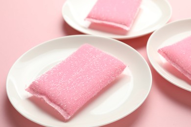 Photo of Sponges and plates on pink background, closeup