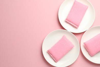 Photo of Sponges and plates on pink background, flat lay. Space for text