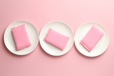 Sponges and plates on pink background, flat lay