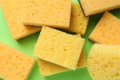 Photo of Many sponges on green background, flat lay