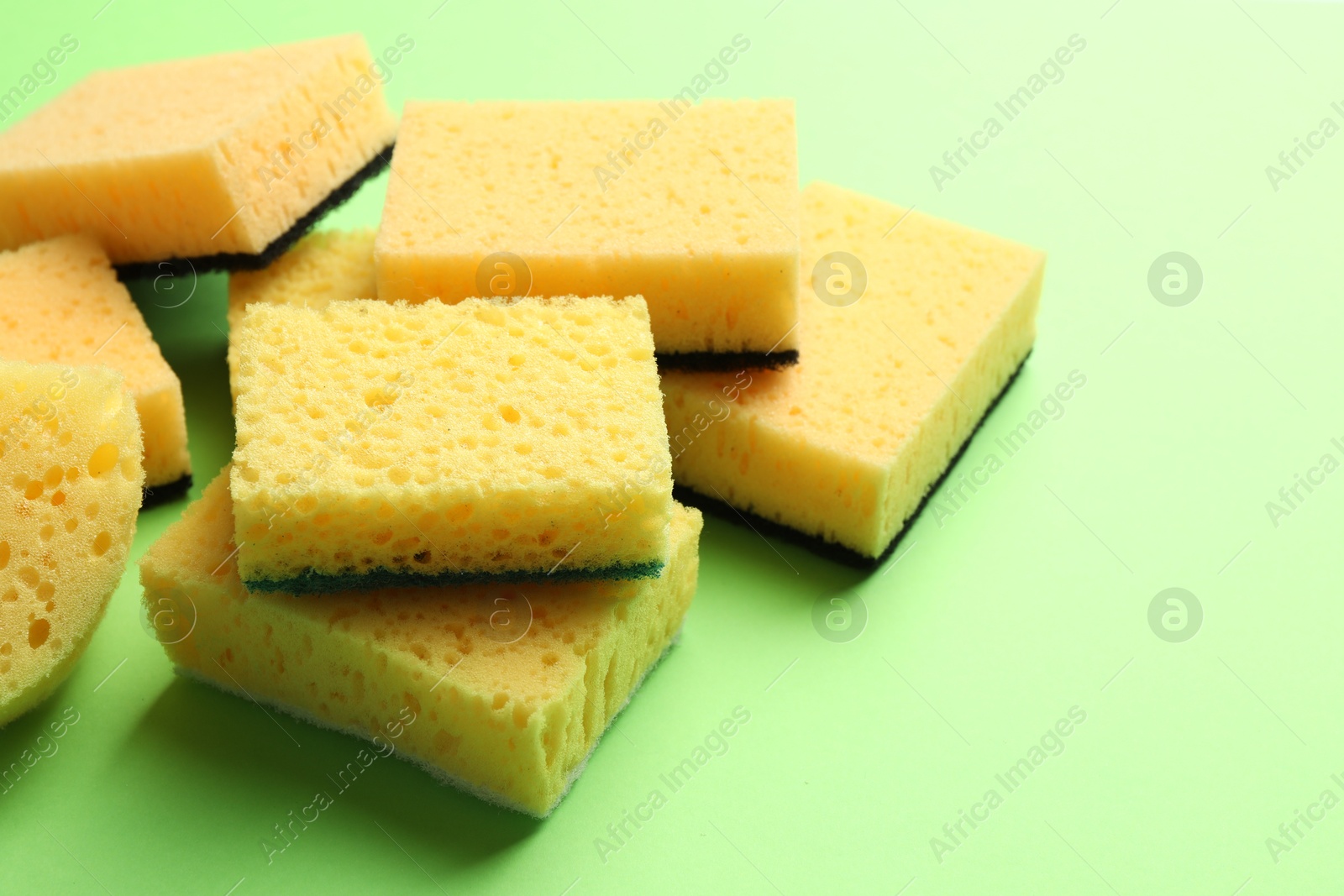 Photo of Pile of sponges on green background, closeup. Space for text