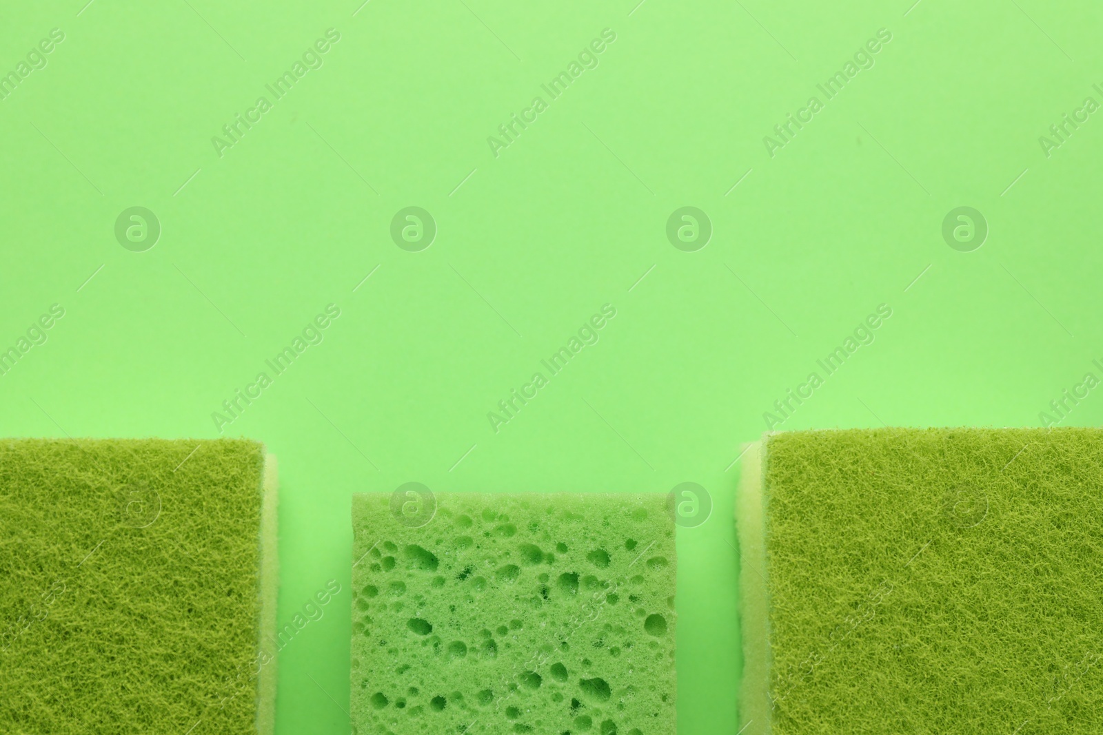 Photo of Sponges on green background, flat lay. Space for text