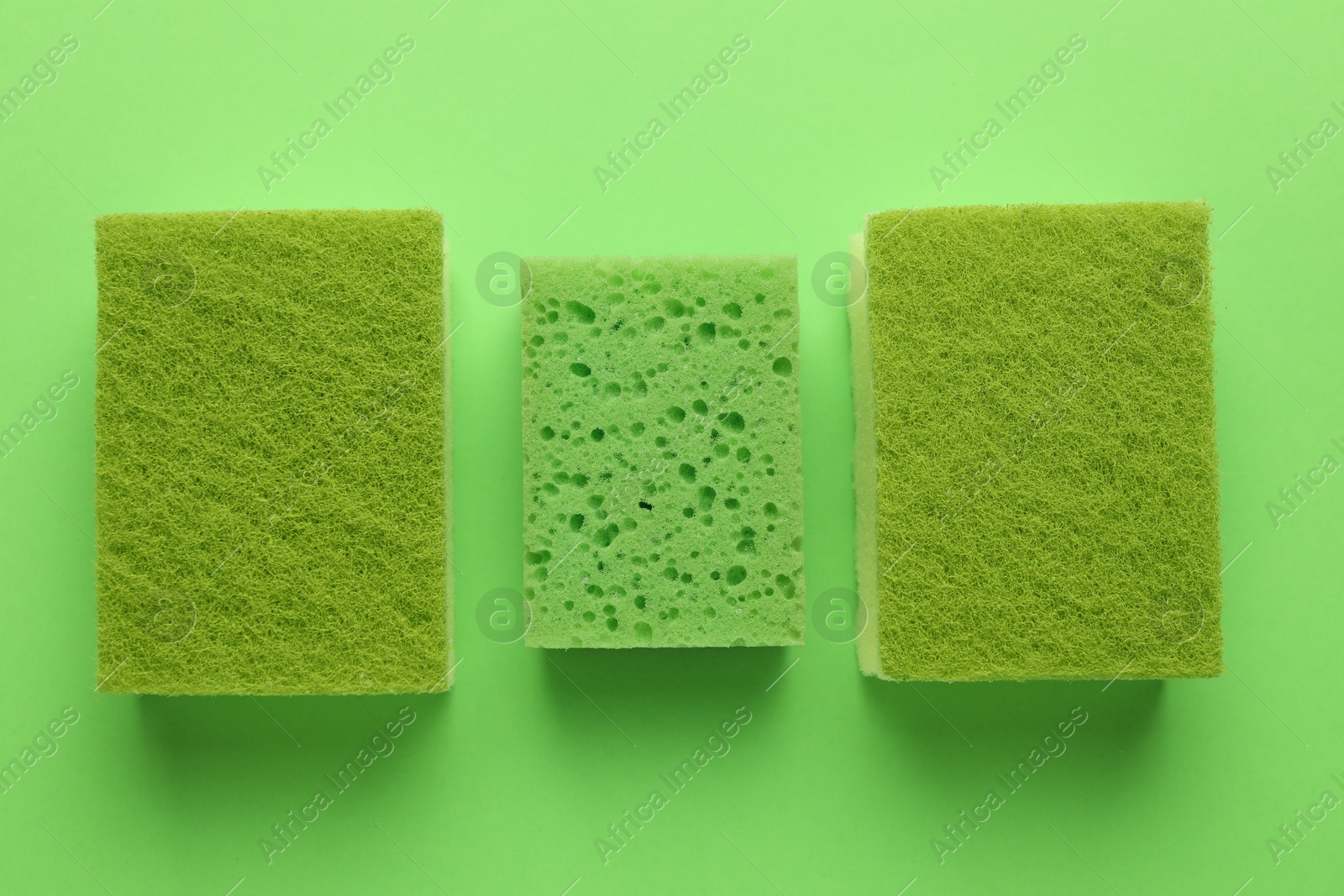 Photo of Group of sponges on green background, flat lay