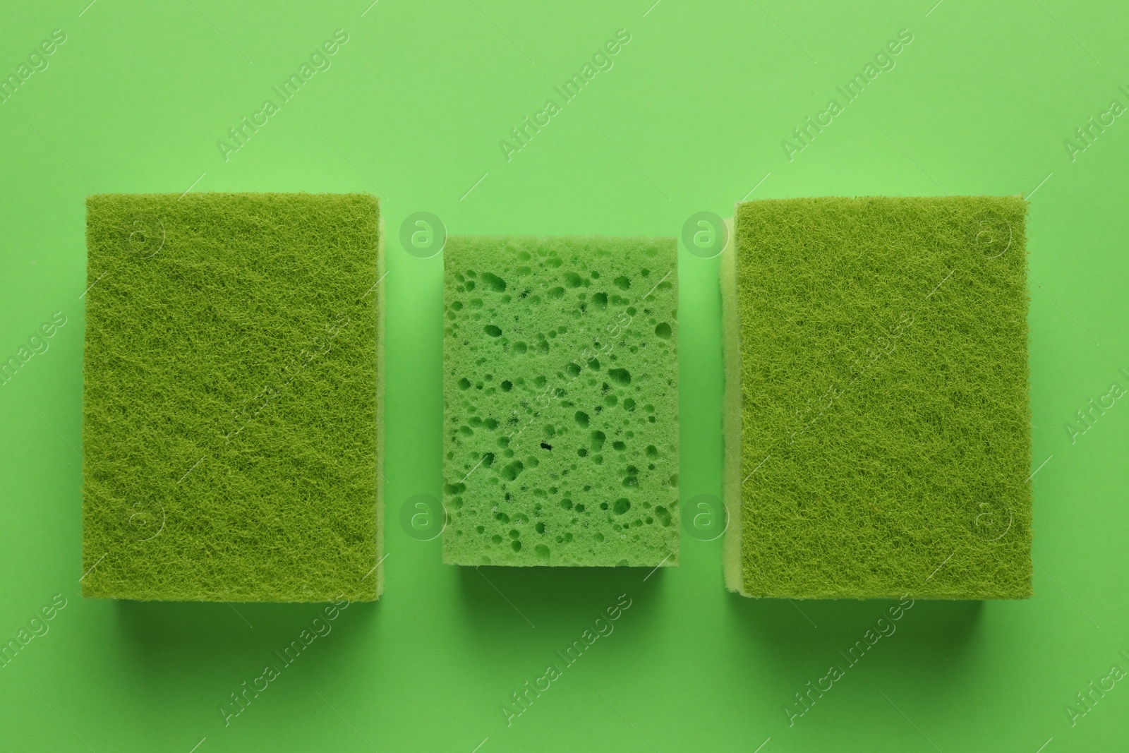 Photo of Group of sponges on green background, flat lay