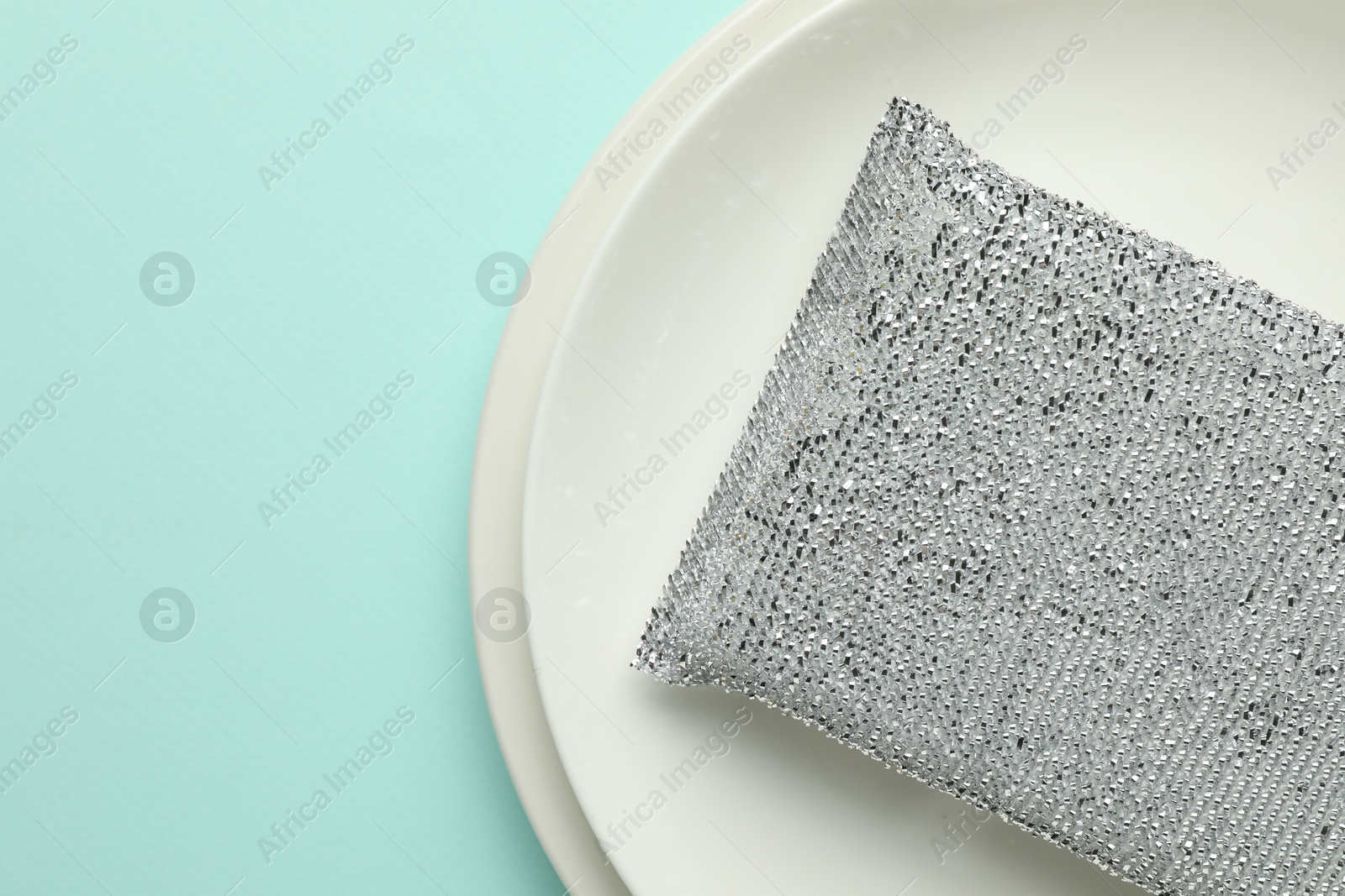 Photo of One sponge and plates on light blue background, top view. Space for text