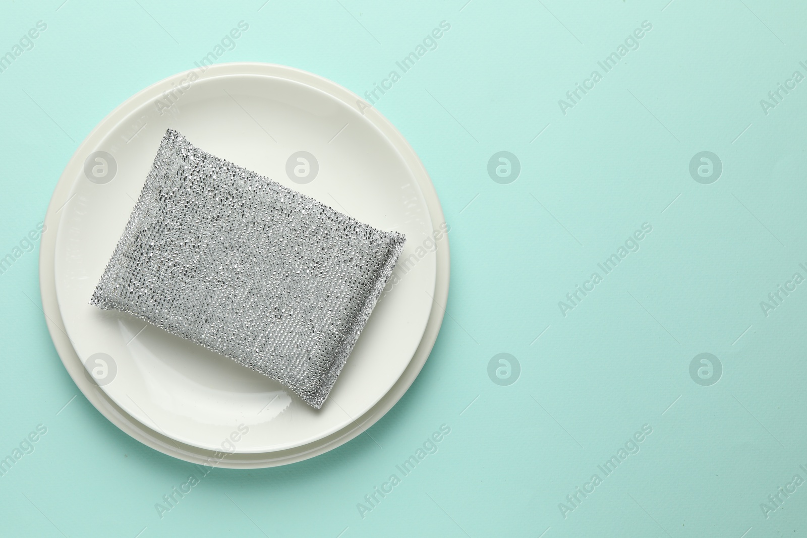 Photo of One sponge and plates on light blue background, top view. Space for text