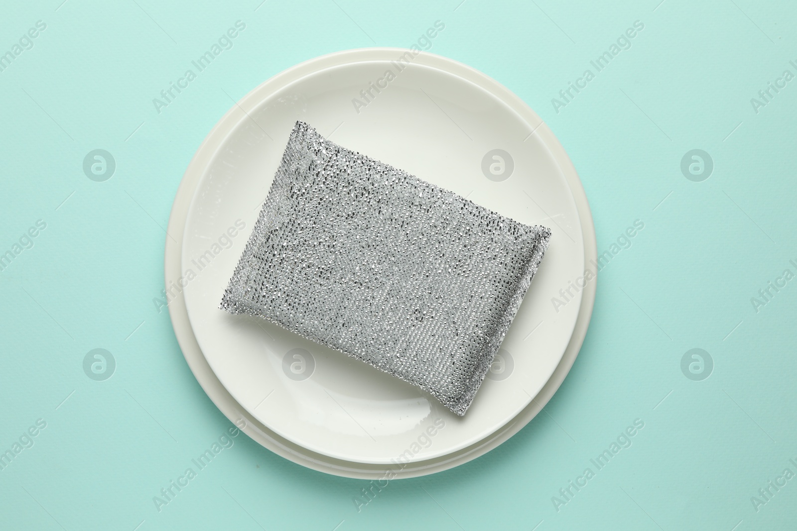 Photo of One sponge and plates on light blue background, top view