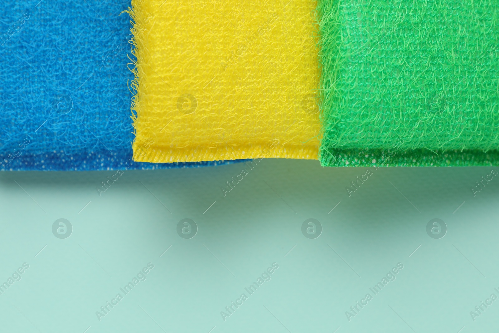 Photo of Color sponges on light blue background, top view. Space for text