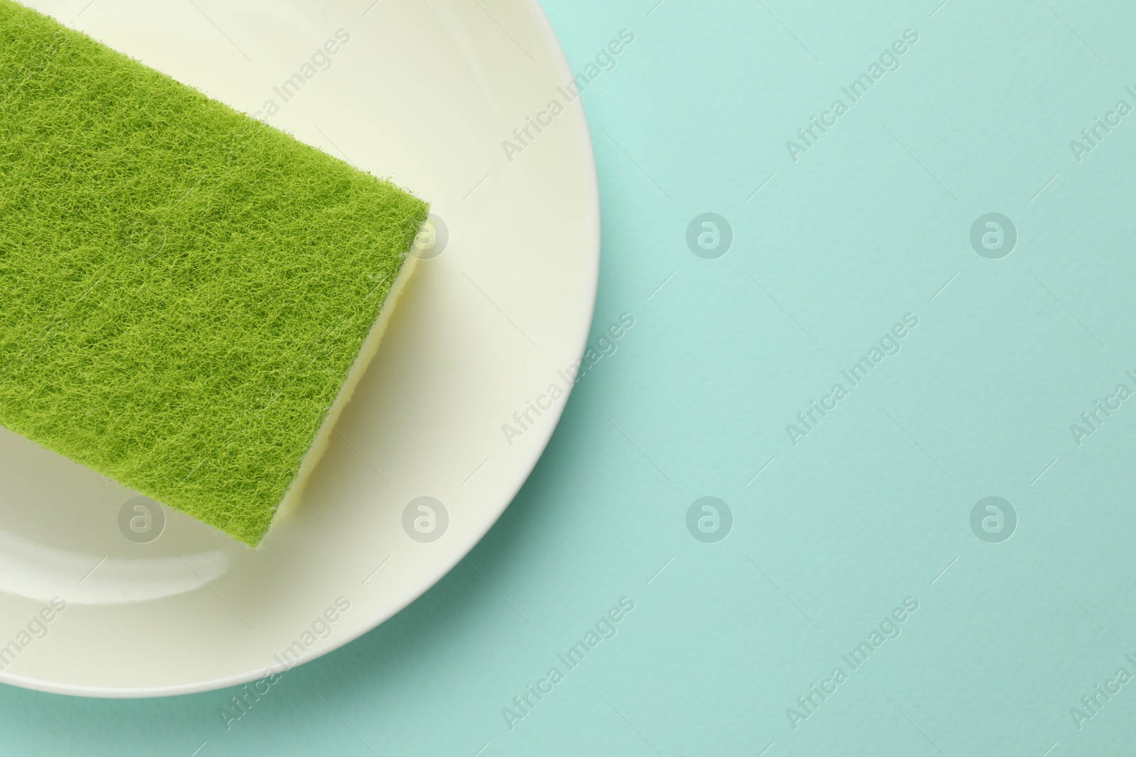 Photo of One sponge and plate on light blue background, top view. Space for text