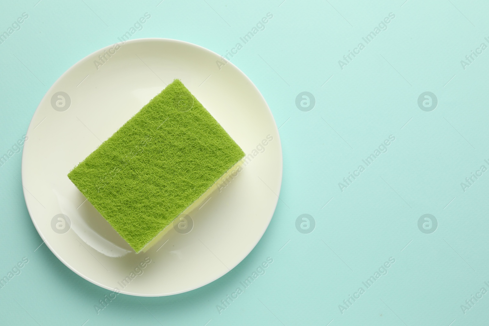 Photo of One sponge and plate on light blue background, top view. Space for text