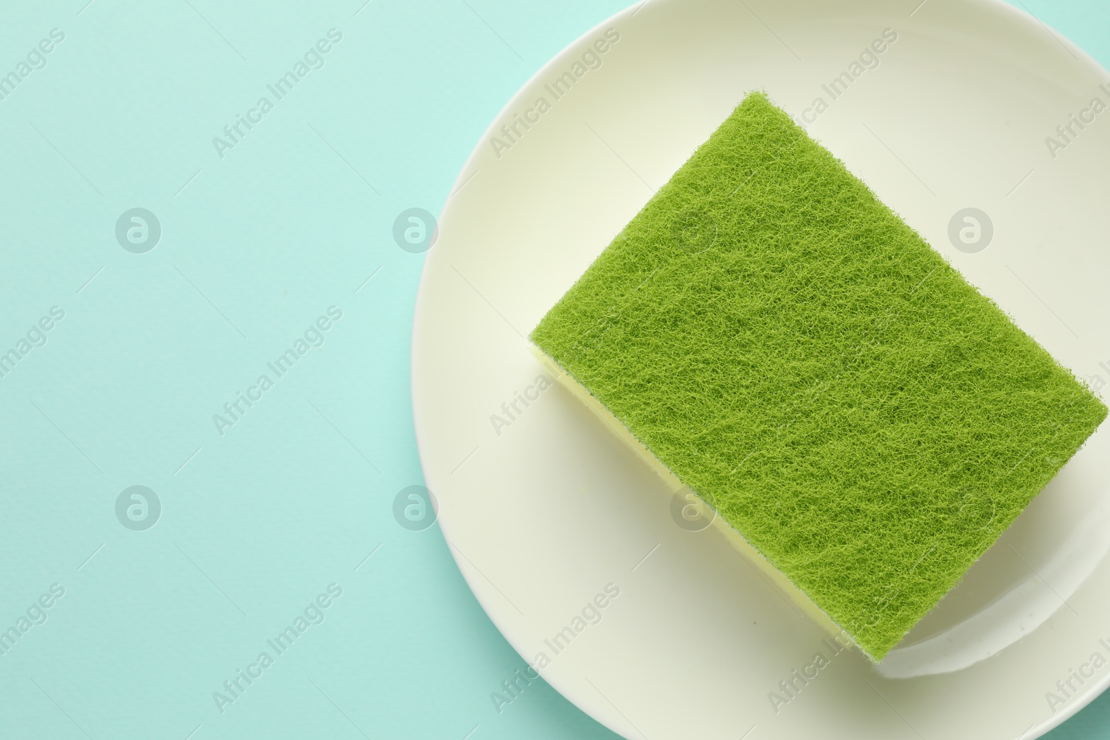 Photo of One sponge and plate on light blue background, top view. Space for text