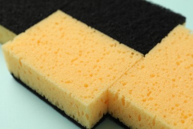 Photo of Color sponges on light blue background, closeup