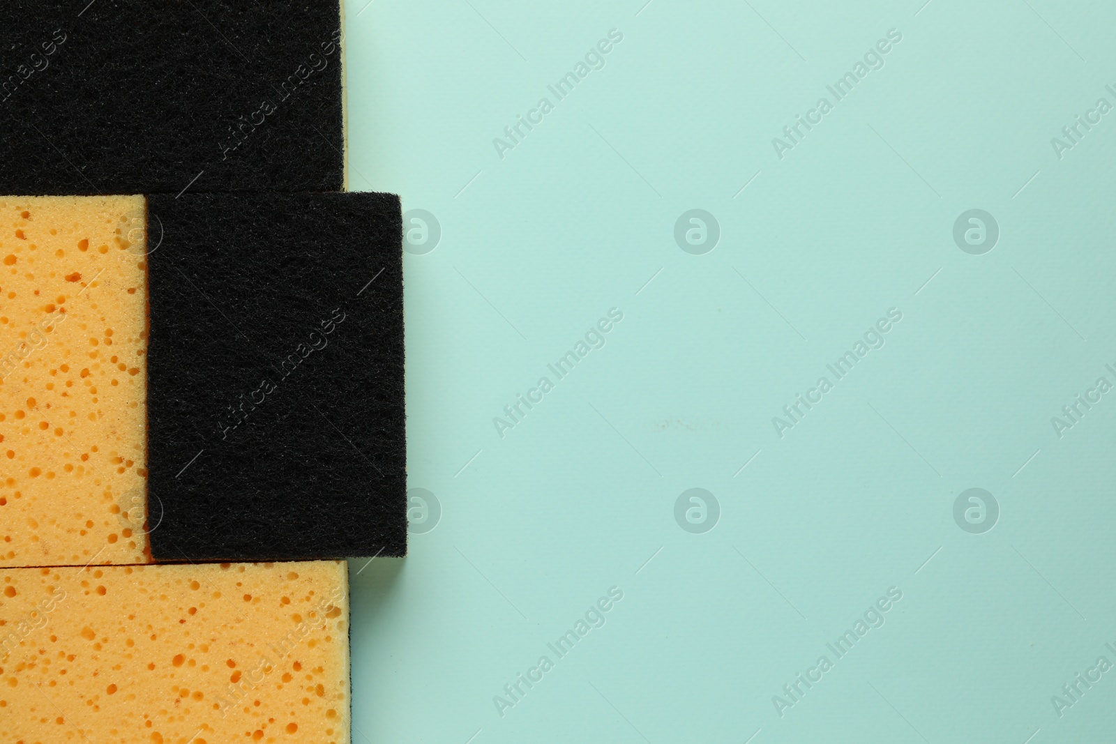 Photo of Sponges on light blue background, top view. Space for text