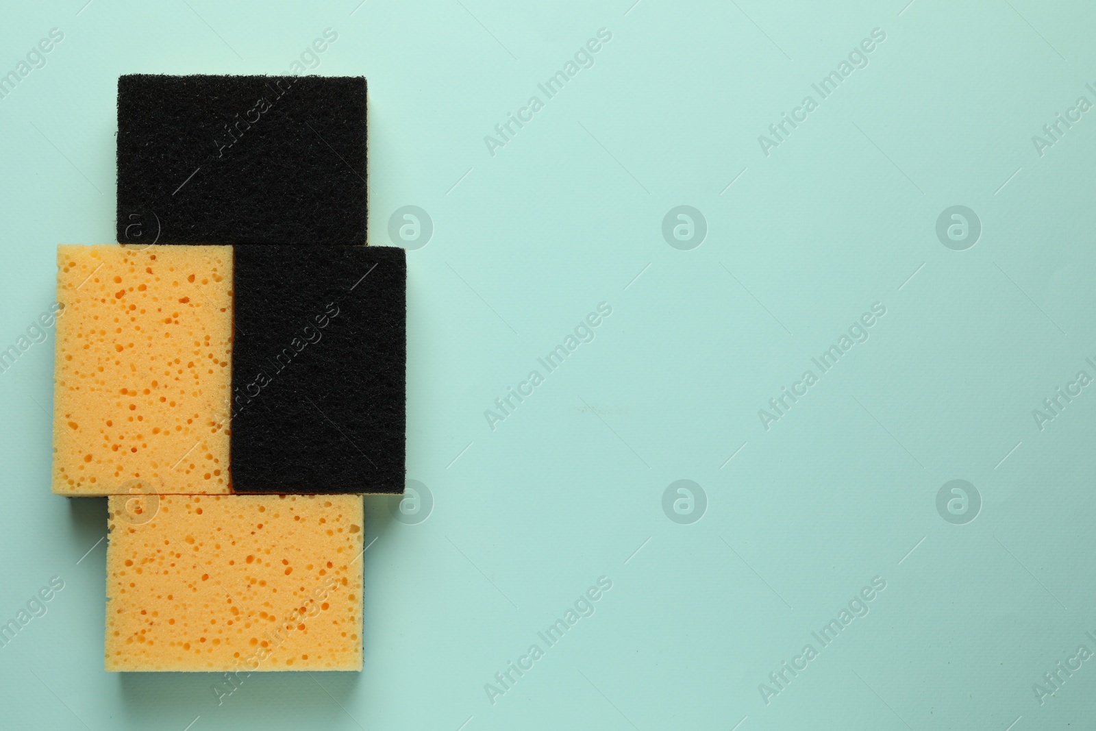 Photo of Sponges on light blue background, top view. Space for text