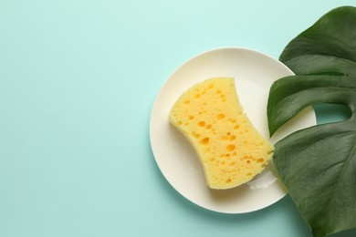 Photo of One sponge, plate and monstera leaf on light blue background, top view. Space for text