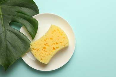 Photo of One sponge, plate and monstera leaf on light blue background, top view. Space for text