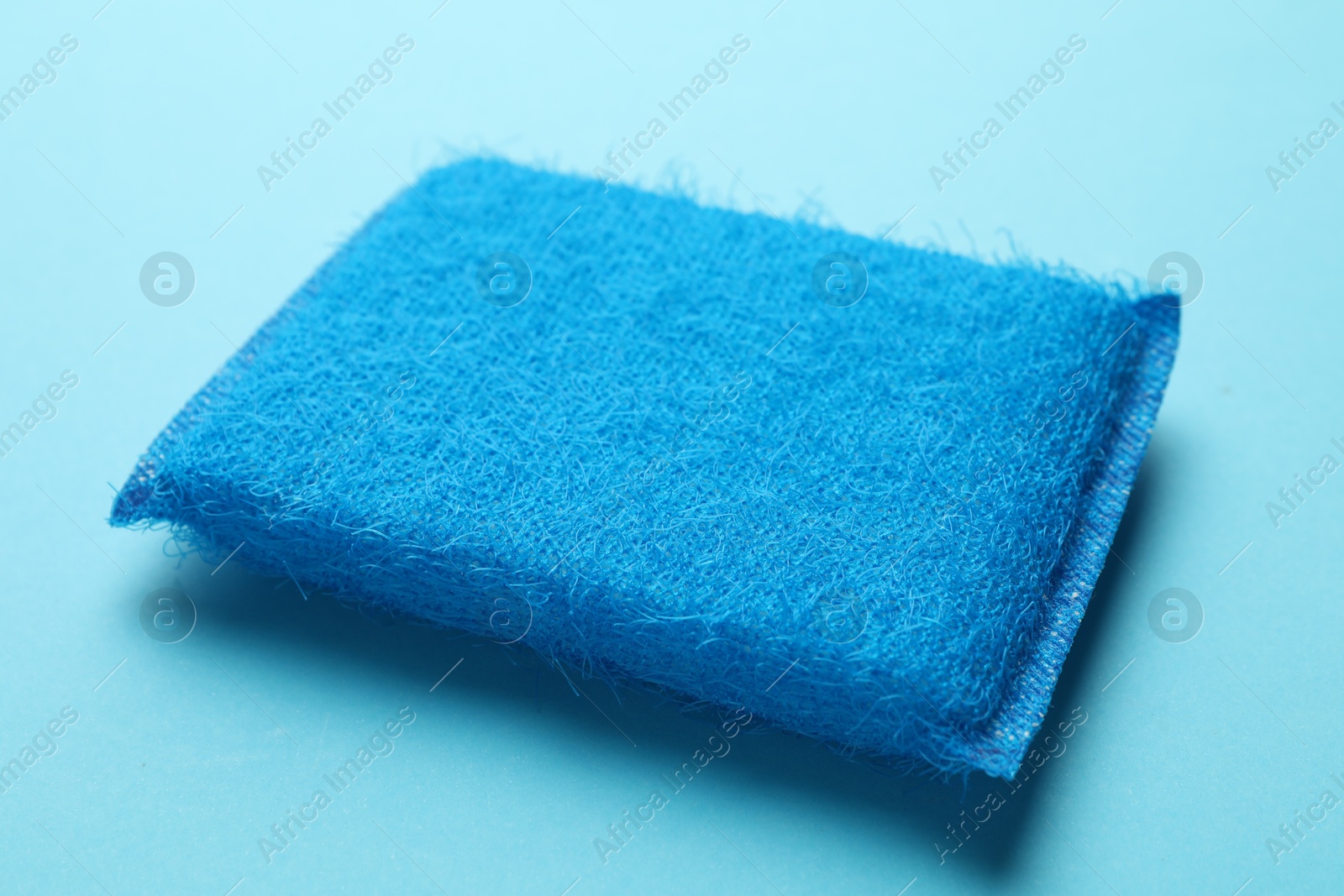 Photo of One sponge on light blue background, closeup