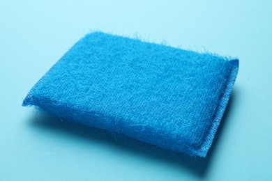 Photo of One sponge on light blue background, closeup