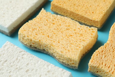 Photo of Many sponges on light blue background, closeup