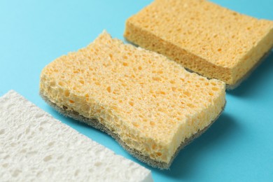 Photo of Many sponges on light blue background, closeup