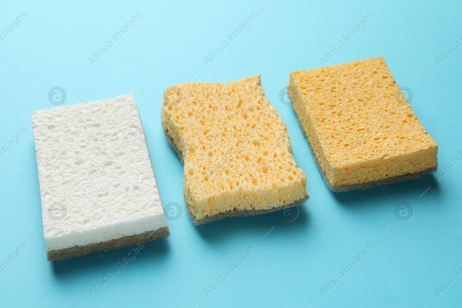 Photo of Many sponges on light blue background, closeup