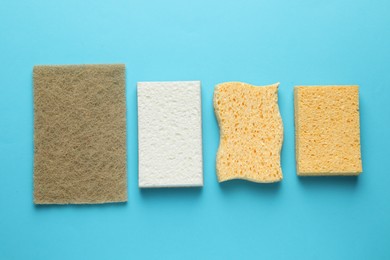 Photo of Many sponges on light blue background, flat lay