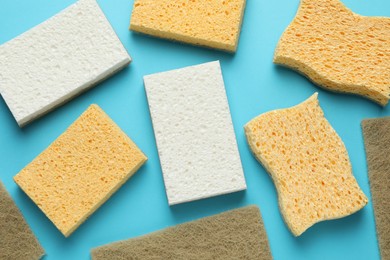 Photo of Many sponges on light blue background, flat lay