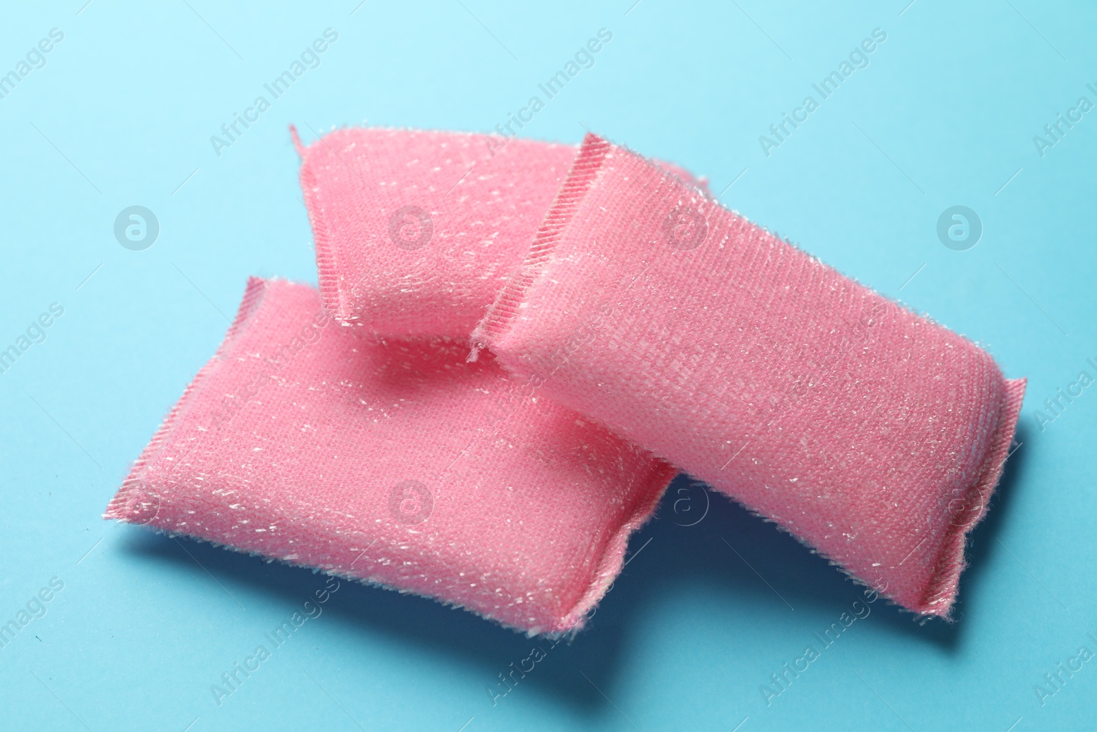 Photo of Pink sponges on light blue background, closeup