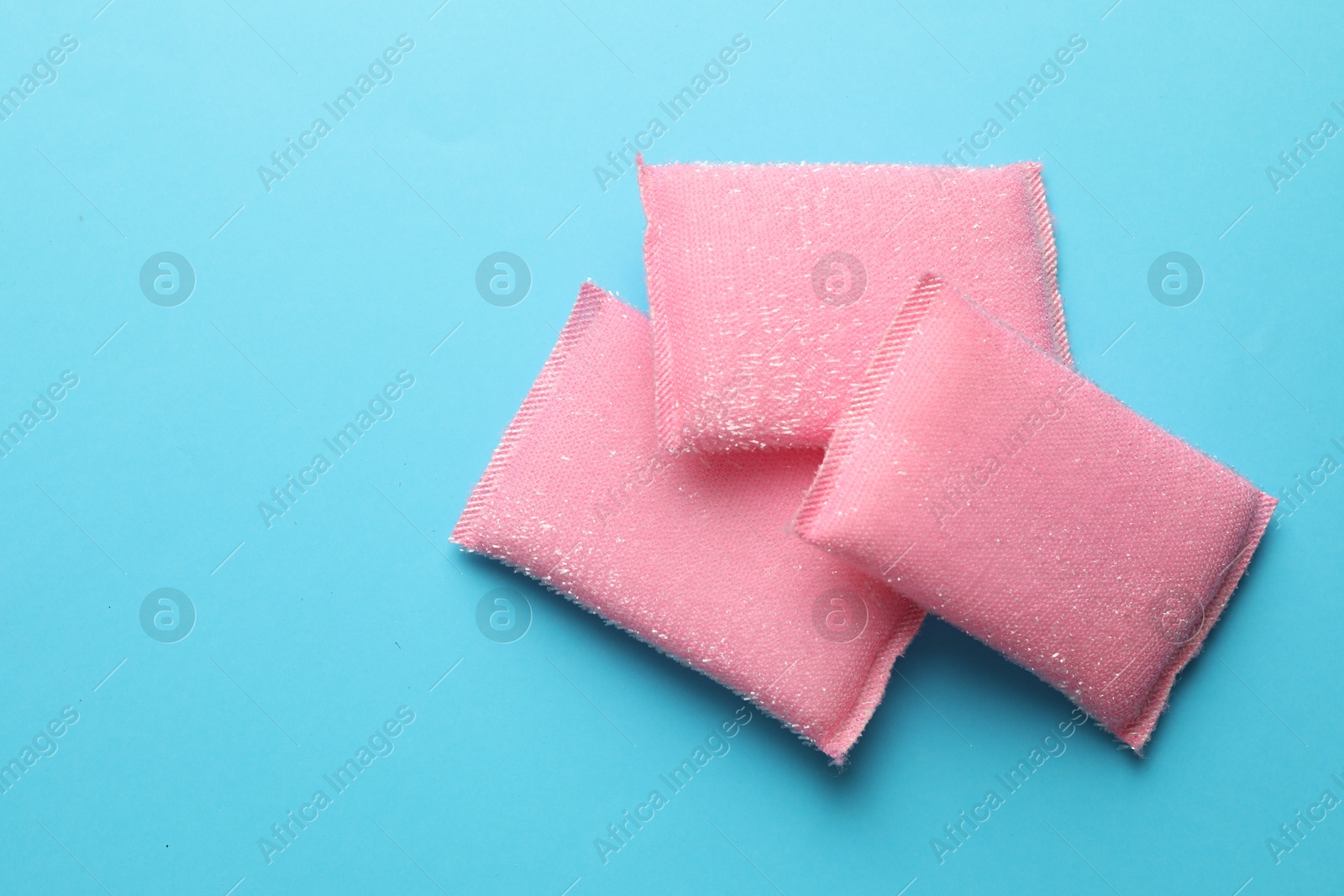 Photo of Pink sponges on light blue background, top view. Space for text