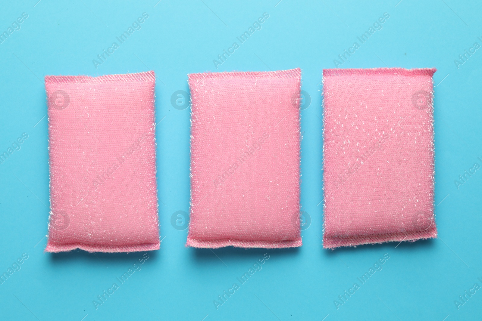 Photo of Pink sponges on light blue background, flat lay