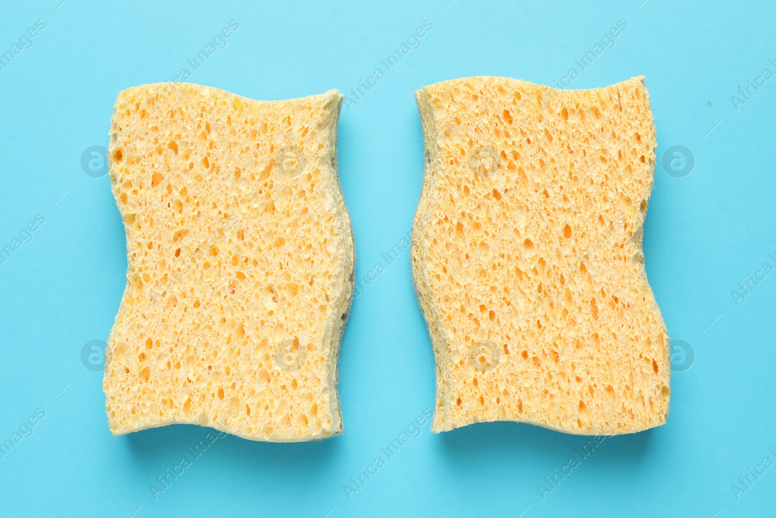 Photo of Two yellow sponges on light blue background, flat lay