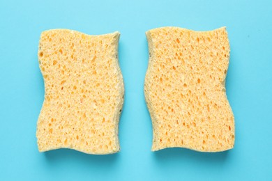 Photo of Two yellow sponges on light blue background, flat lay