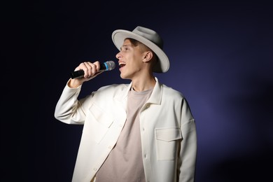 Photo of Talented young man singing on dark background