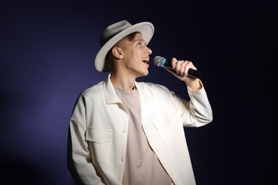 Photo of Talented young man singing on dark background