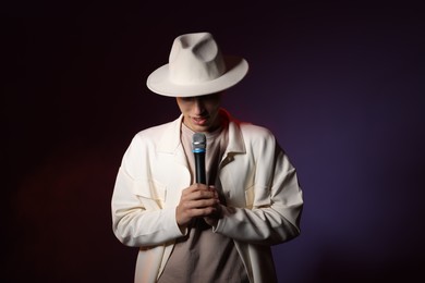 Photo of Talented young man singing on dark background