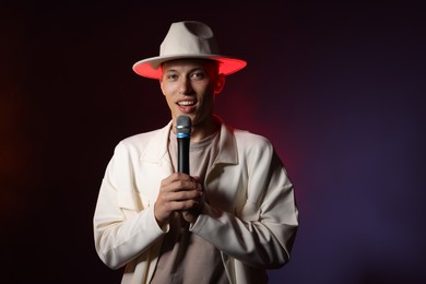 Photo of Talented young man singing on dark background. Space for text