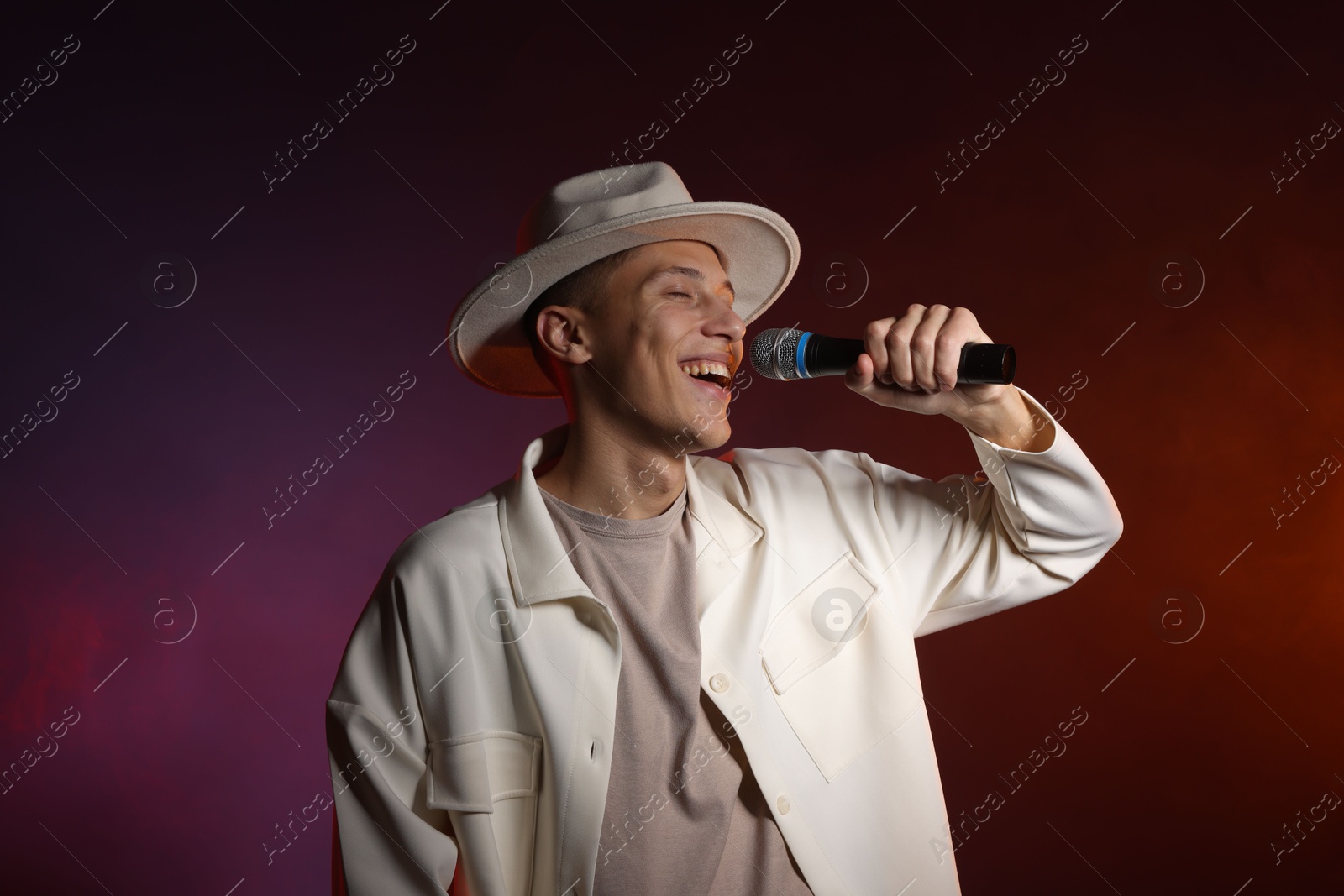 Photo of Talented singer performing on dark background with color lights