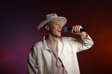 Photo of Talented singer performing on dark background with color lights