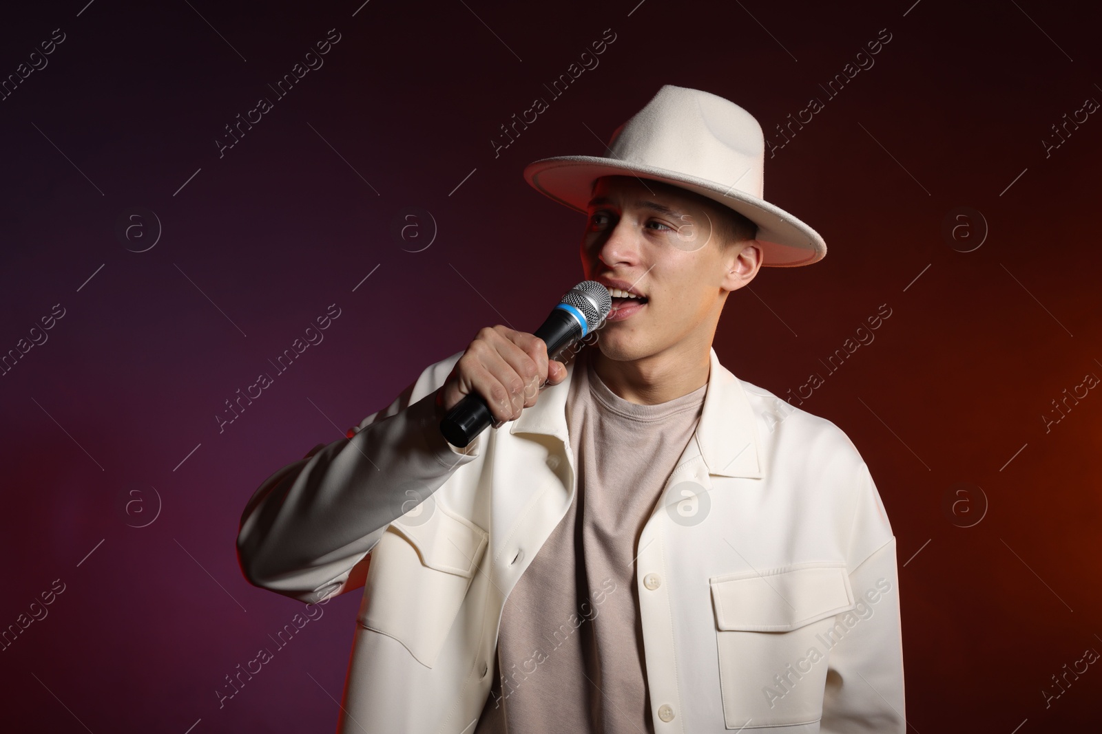 Photo of Talented singer performing on dark background with color lights