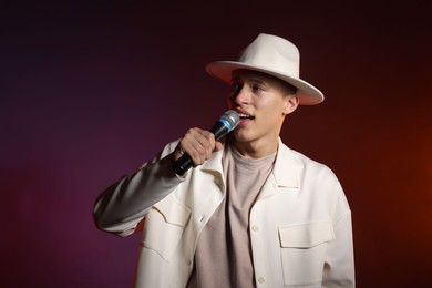 Photo of Talented singer performing on dark background with color lights