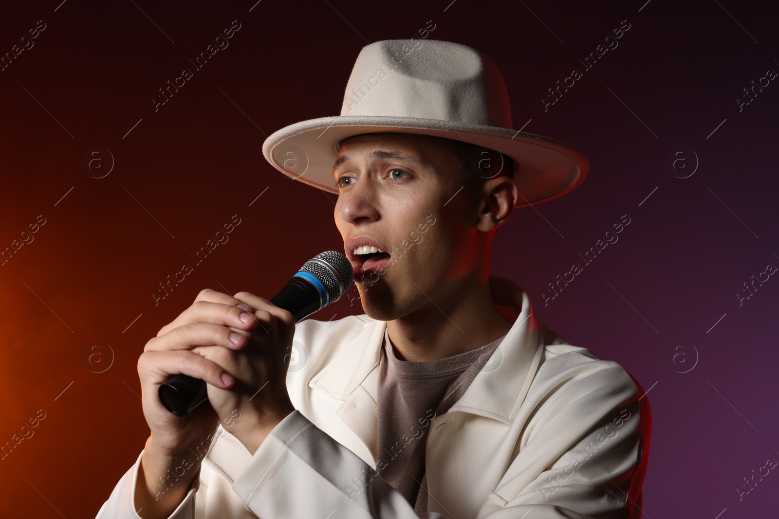 Photo of Talented singer performing on dark background with color lights