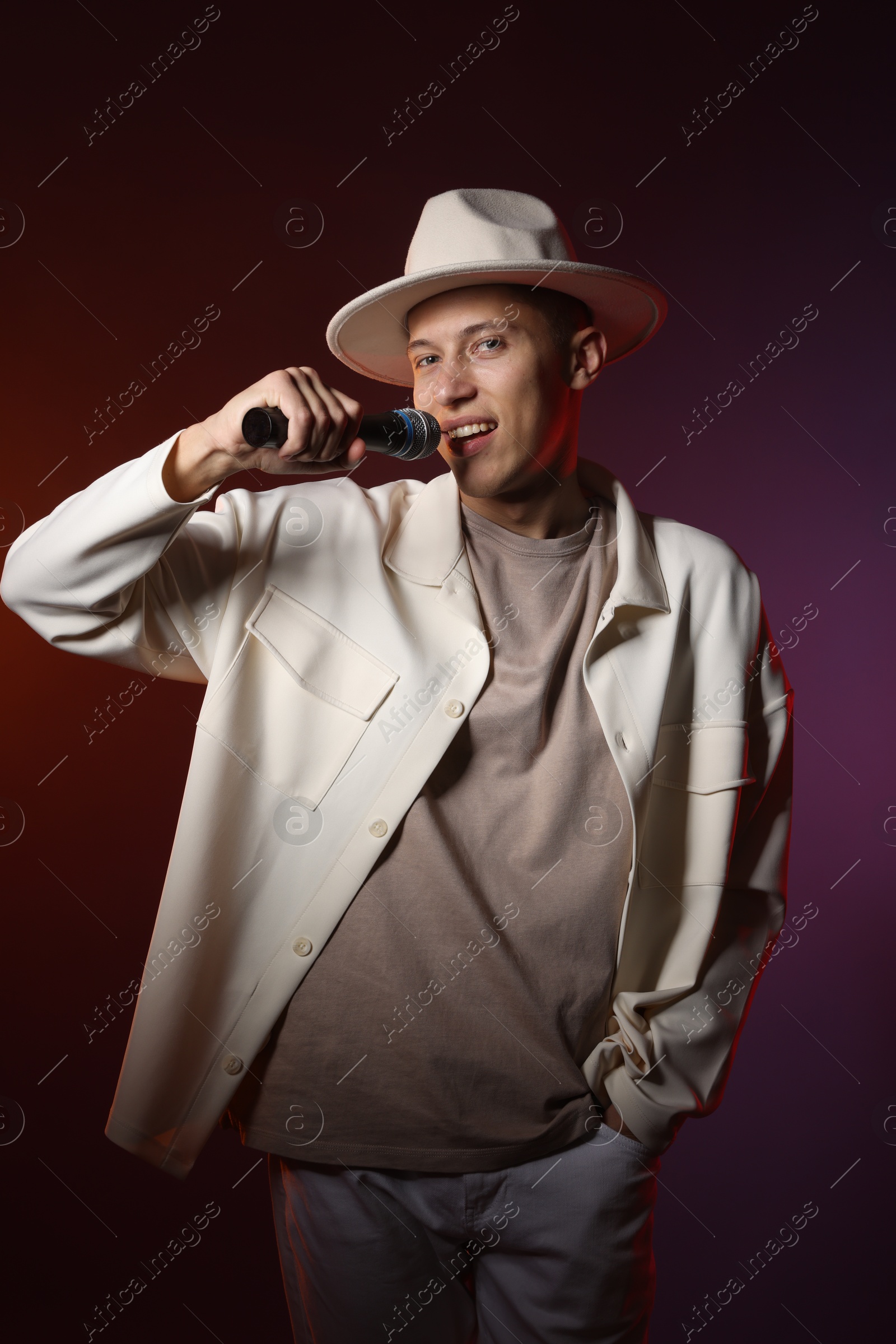 Photo of Talented singer performing on dark background with color lights