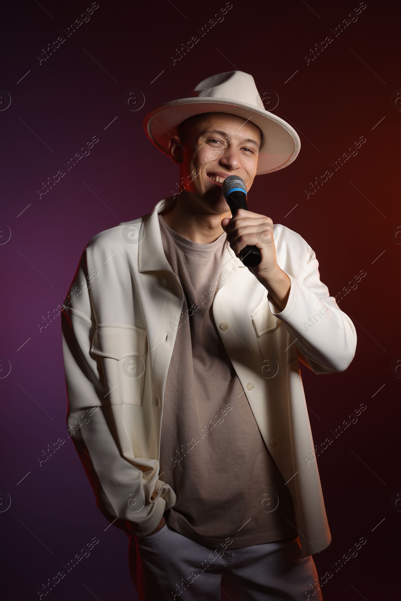 Photo of Talented singer performing on dark background with color lights