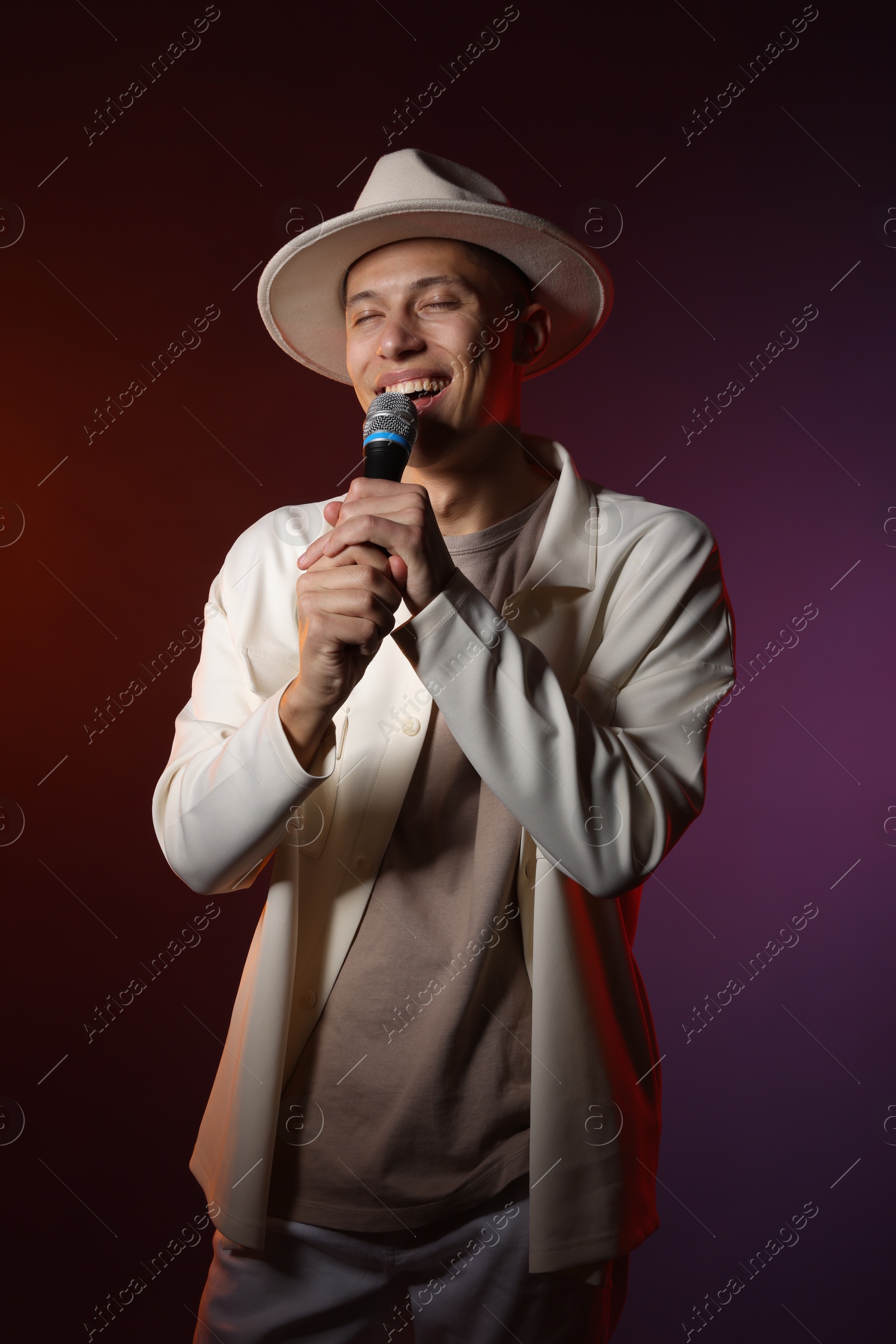 Photo of Talented singer performing on dark background with color lights